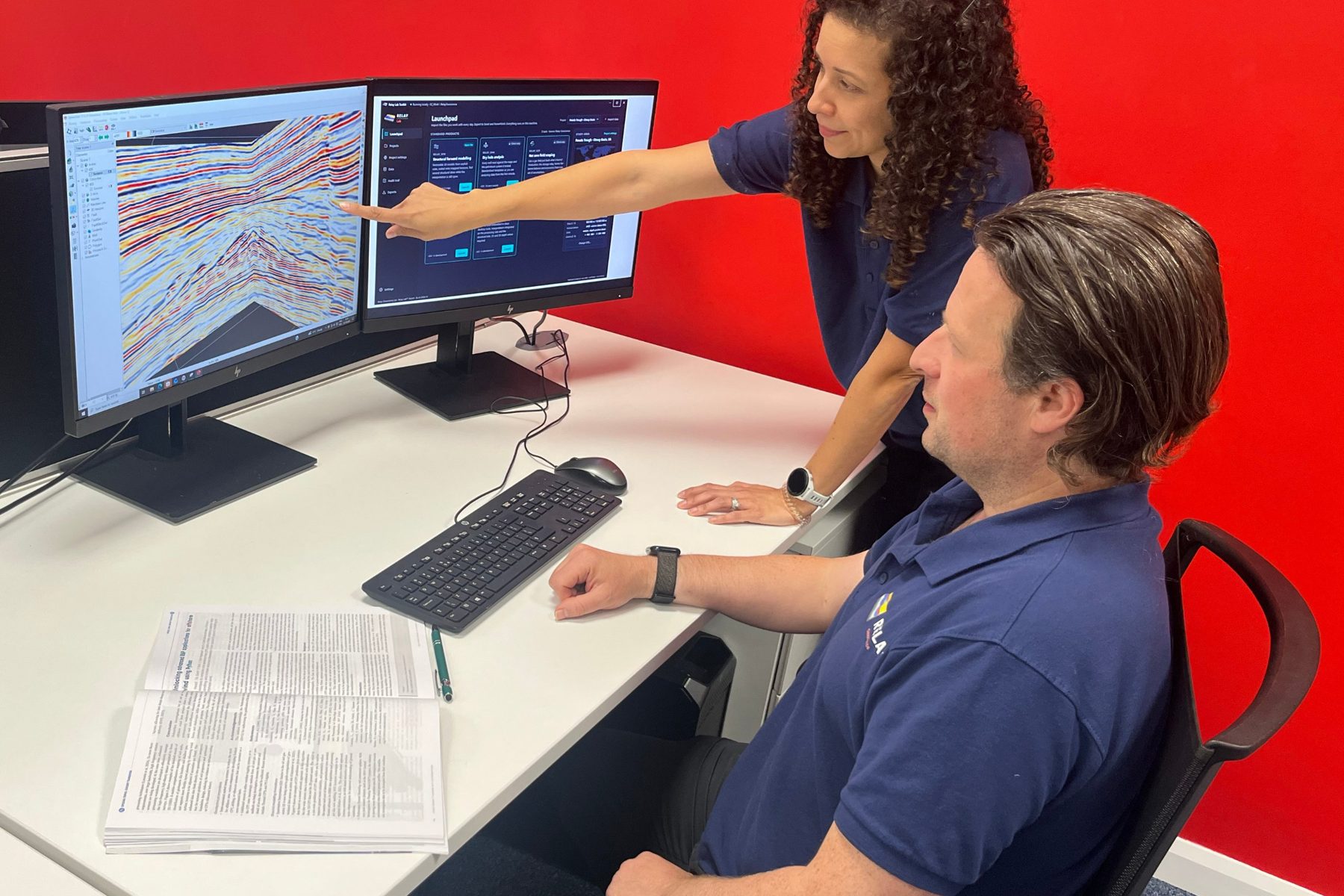 Two Relay geoscientists at a desk: a seismic section on one screen and the Relay Lab Toolkit launchpad on the other